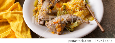 A plate holds rice and stewed quail, showing a mix of vegetables. The meal is placed on a plain surface, ready to be enjoyed for breakfast or lunch, banner A plate holds rice and stewed quail, showing a mix of vegetables. The meal is placed on a plain surface, ready to be enjoyed for breakfast or lunch, banner 142314587