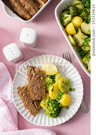 A plate holds boiled potatoes, turkey meat pie, broccoli, and green peas. This breakfast is healthy and gluten free, perfect for a good start to the day A plate holds boiled potatoes, turkey meat pie, broccoli, and green peas. This breakfast is healthy and gluten free, perfect for a good start to the day 142314619