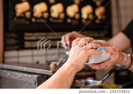 Customer buying fresh chimney cake pastry at street food bakery Customer buying fresh chimney cake pastry at street food bakery 142314652