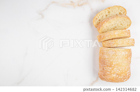 Freshly baked ciabatta bread loaf with several slices cut and arranged on a marble countertop, showcasing the crusty exterior and soft interior texture. space for text Freshly baked ciabatta bread loaf with several slices cut and arranged on a marble countertop, showcasing the crusty exterior and soft interior texture. space for text 142314682