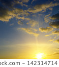 Scenic Dramatic Sunrise with Sunbeams Breaking Through Cumulus Clouds. Vibrant Blue and Yellow Celestial Texture for Natural Backgrounds and Design. 142314714
