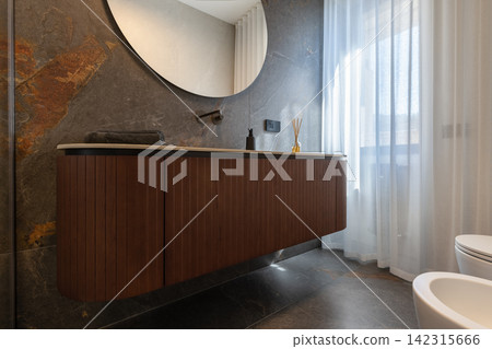 Bathroom vanity shown with freestanding bathtub against charcoal panels and warm wood Bathroom vanity shown with freestanding bathtub against charcoal panels and warm wood 142315666