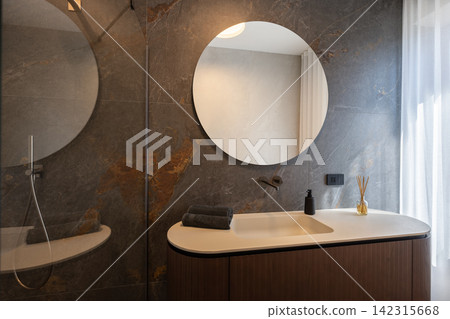Bathroom vanity beside a glass shower enclosure under cool diffused daylight Bathroom vanity beside a glass shower enclosure under cool diffused daylight 142315668