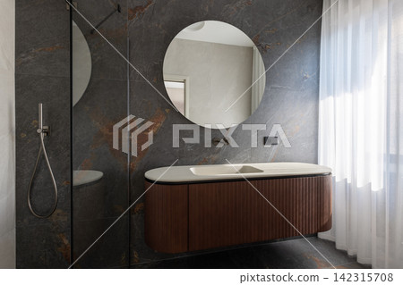 Empty bathroom vanity beside a walk-in shower among dark finishes and soft highlights Empty bathroom vanity beside a walk-in shower among dark finishes and soft highlights 142315708