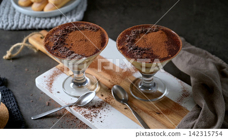 Two glasses of classic Italian tiramisu topped with cocoa powder and dark chocolate shavings Two glasses of classic Italian tiramisu topped with cocoa powder and dark chocolate shavings 142315754