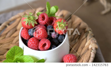 Fresh Berries in a White Ceramic Bowl on a Woven Basket Platter Fresh Berries in a White Ceramic Bowl on a Woven Basket Platter 142315763