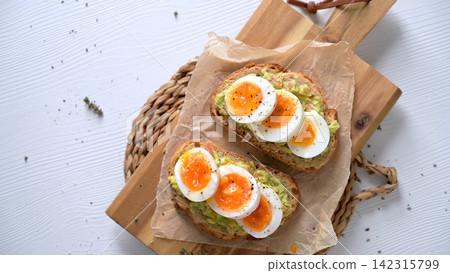 Avocado toast with sliced boiled eggs on wooden board Avocado toast with sliced boiled eggs on wooden board 142315799