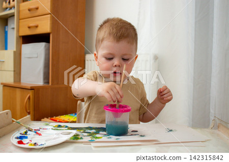 Toddler using hands and brush to create art. Fine and gross motor skills grow. Art therapy through free expression. Early childhood creativity without digital distractions Toddler using hands and brush to create art. Fine and gross motor skills grow. Art therapy through free expression. Early childhood creativity without digital distractions 142315842