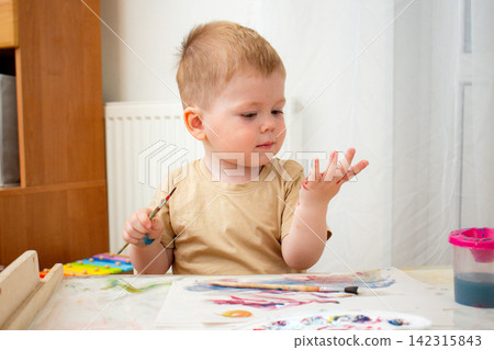 Child mixing watercolors with fingers on paper. Tactile learning about color blending. Sensory play strengthens neural connections. Art therapy and artistic development Child mixing watercolors with fingers on paper. Tactile learning about color blending. Sensory play strengthens neural connections. Art therapy and artistic development 142315843