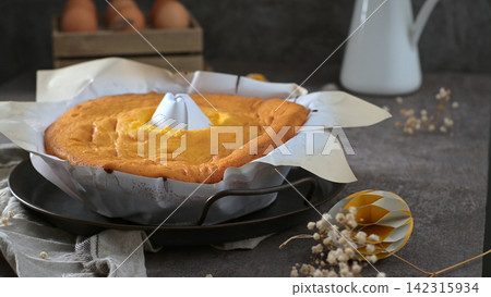 Freshly Baked Chiffon Cake in Parchment Paper on a Rustic Dark Table Freshly Baked Chiffon Cake in Parchment Paper on a Rustic Dark Table 142315934