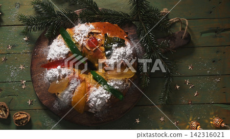 Traditional king cake with candied fruit and powdered sugar on a wooden board Traditional king cake with candied fruit and powdered sugar on a wooden board 142316021