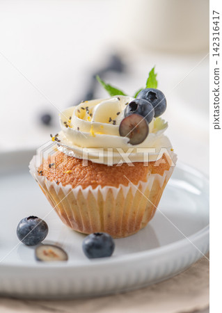 Cupcake with white frosting and fresh blueberries on a plate Cupcake with white frosting and fresh blueberries on a plate 142316417