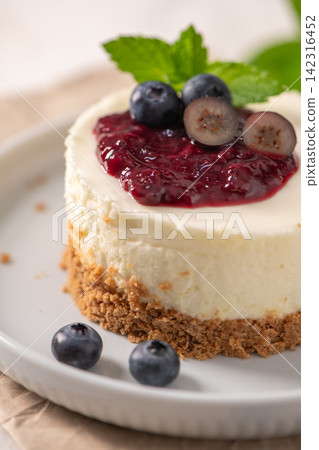 Macro view of a mini cheesecake with glossy berry compote and fresh mint Macro view of a mini cheesecake with glossy berry compote and fresh mint 142316452