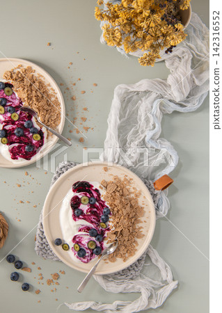Top Down Flat Lay of Yogurt Bowls with Blueberry Swirl and Whole Grain Flakes Top Down Flat Lay of Yogurt Bowls with Blueberry Swirl and Whole Grain Flakes 142316552