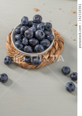 Fresh blueberries in a small bowl on a woven mat Fresh blueberries in a small bowl on a woven mat 142316561