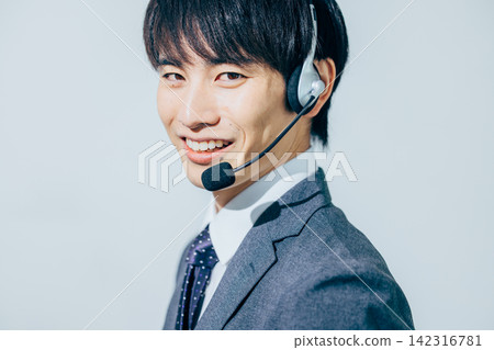一名身穿西裝、戴著耳機的男子。 142316781