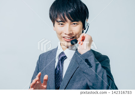 一名身穿西裝、戴著耳機的男子。 142316783