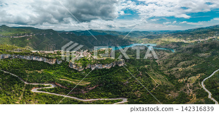 Aerial panoramic view of Siurana village and Siurana Reservoir surrounded by dramatic cliffs, winding mountain roads and rugged landscapes Aerial panoramic view of Siurana village and Siurana Reservoir surrounded by dramatic cliffs, winding mountain roads and rugged landscapes 142316839