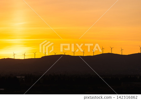Wind turbines on mountain ridge at sunset representing renewable energy generation and sustainable electricity production Wind turbines on mountain ridge at sunset representing renewable energy generation and sustainable electricity production 142316862