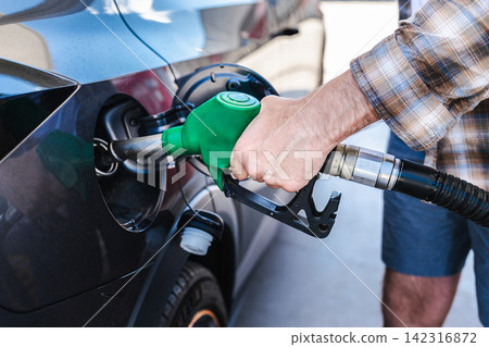 Man refueling modern vehicle with green gasoline nozzle at fuel station Man refueling modern vehicle with green gasoline nozzle at fuel station 142316872