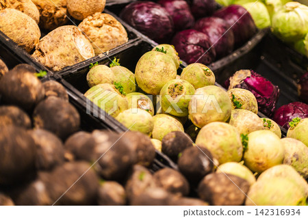 Assorted root vegetables and cabbage displayed in supermarket produce section with fresh organic grocery food selection Assorted root vegetables and cabbage displayed in supermarket produce section with fresh organic grocery food selection 142316934