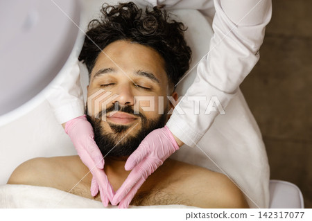 Man receiving facial massage in a beauty salon Man receiving facial massage in a beauty salon 142317077