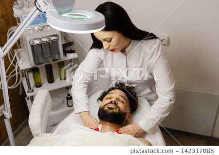Man receiving professional facial massage and skincare treatment Man receiving professional facial massage and skincare treatment 142317088