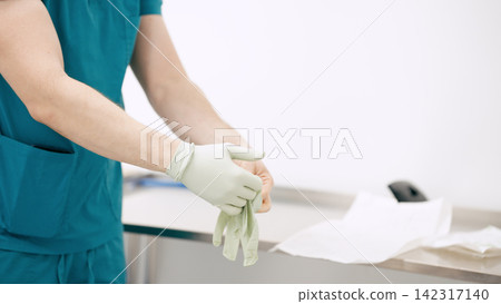 Doctor putting on surgical glove for hygiene and safety Doctor putting on surgical glove for hygiene and safety 142317140