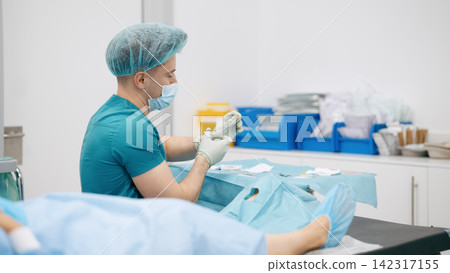 Surgeon preparing medical instruments for patient surgery 142317155