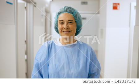 Female surgeon smiling wearing scrubs in hospital hallway Female surgeon smiling wearing scrubs in hospital hallway 142317172