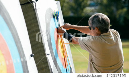 Older man hitting target while practicing archery 142317195