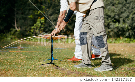 Senior man preparing bow for archery practice Senior man preparing bow for archery practice 142317197