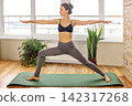 Yoga practice in a bright room with large windows and plants 142317268