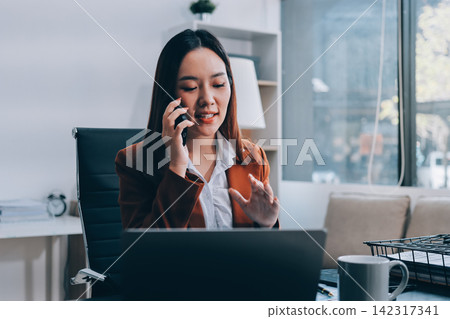 Female secretary who works in the office is talking on the phone with someone. Female secretary who works in the office is talking on the phone with someone. 142317341