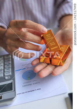 Physical gold bars on investor's hand at office desk. Concept for secure financial investment and wealth preservation. Physical gold bars on investor's hand at office desk. Concept for secure financial investment and wealth preservation. 142317449
