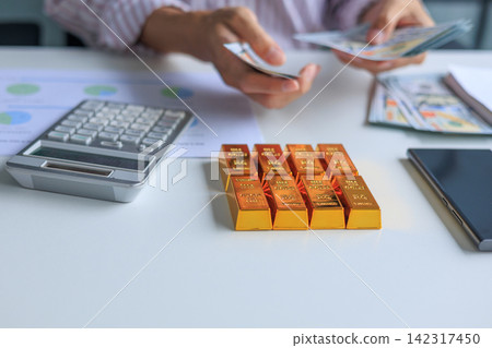 Banker, Accountant or Investor Counting Money with Gold Bars on the Table. Gold Commodity Trading and Market Analysis in Modern Office. Banker, Accountant or Investor Counting Money with Gold Bars on the Table. Gold Commodity Trading and Market Analysis in Modern Office. 142317450