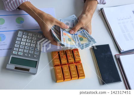 Banker, Accountant or Investor Counting Money with Gold Bars on the Table. Gold Commodity Trading and Market Analysis in Modern Office. 142317451