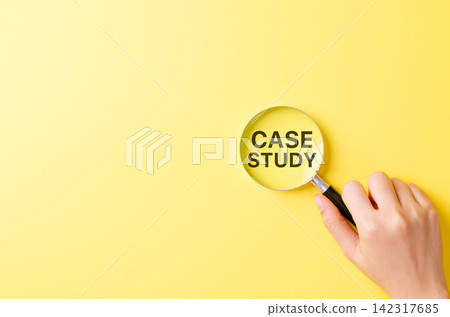 Case study research concept, hand holding magnifying glass focusing on bold text CASE STUDY over yellow background symbolizing detailed investigation, learning method and business or academic analysis 142317685