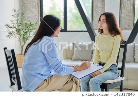 Young thoughtful woman listening to female psychologist in office 142317840