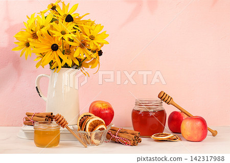 Autumn banner with a beautiful bouquet of rudbeckia in a vase, honey, apples, dried orange, cinnamon and star anise on an elegant background, autumn greeting and gratitude concept, cozy composition Autumn banner with a beautiful bouquet of rudbeckia in a vase, honey, apples, dried orange, cinnamon and star anise on an elegant background, autumn greeting and gratitude concept, cozy composition 142317988