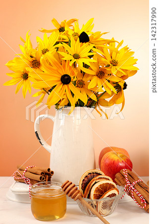Autumn banner with a beautiful bouquet of rudbeckia in a vase, honey, apples, dried orange, cinnamon and star anise on an elegant background, autumn greeting and gratitude concept, cozy composition Autumn banner with a beautiful bouquet of rudbeckia in a vase, honey, apples, dried orange, cinnamon and star anise on an elegant background, autumn greeting and gratitude concept, cozy composition 142317990