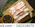 Raw bacon on wooden cutting board on brown background. 142318070