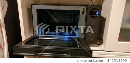 一個造型時尚、功能簡單的微波爐的蓋子被打開，露出了內部照明燈。 142318293