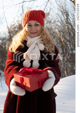Woman offering Christmas gift box toward camera Woman offering Christmas gift box toward camera 142318334