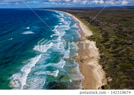 Aerial view of the long sandy shoreline of Sand Dune Beach at Brooms Head, featuring clear turquoise water, coastal dunes and surrounding natural landscape along the Clarence Valley coastline of NSW Aerial view of the long sandy shoreline of Sand Dune Beach at Brooms Head, featuring clear turquoise water, coastal dunes and surrounding natural landscape along the Clarence Valley coastline of NSW 142319674