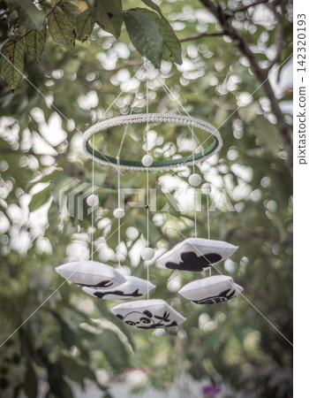 Decorative cot mobile hanging among green foliage Decorative cot mobile hanging among green foliage 142320193