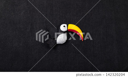 Handmade felt toucan bird decor against a black background with copy space Handmade felt toucan bird decor against a black background with copy space 142320204