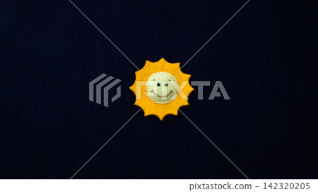 Handmade felt smiling sun decor against a black background with copy space Handmade felt smiling sun decor against a black background with copy space 142320205