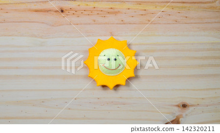 Handmade smiling sun on a wooden background with copy space Handmade smiling sun on a wooden background with copy space 142320211
