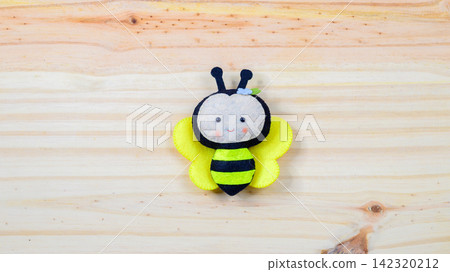 Cute handmade felt bee toy on a wooden background with copy space Cute handmade felt bee toy on a wooden background with copy space 142320212